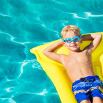 Young Boy Relaxing and Having Fun in Swimming Pool on Yellow Raft. Summer Vacation Fun. Relaxing Lifestyle Concept.